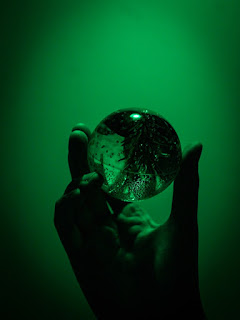 Looking through a dark crystal ball photo by Zaeo on Unsplash - https://unsplash.com/photos/a-person-holding-a-glass-ACUNH8954Pc