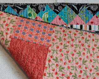 Folded quilt shows part of the border and the peach fabrics making the back of the Hourglass quilt.