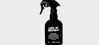 A black spray bottle filled with green tinted liquid with a black domed label with Lord of Misrule body spray in white font on a white background