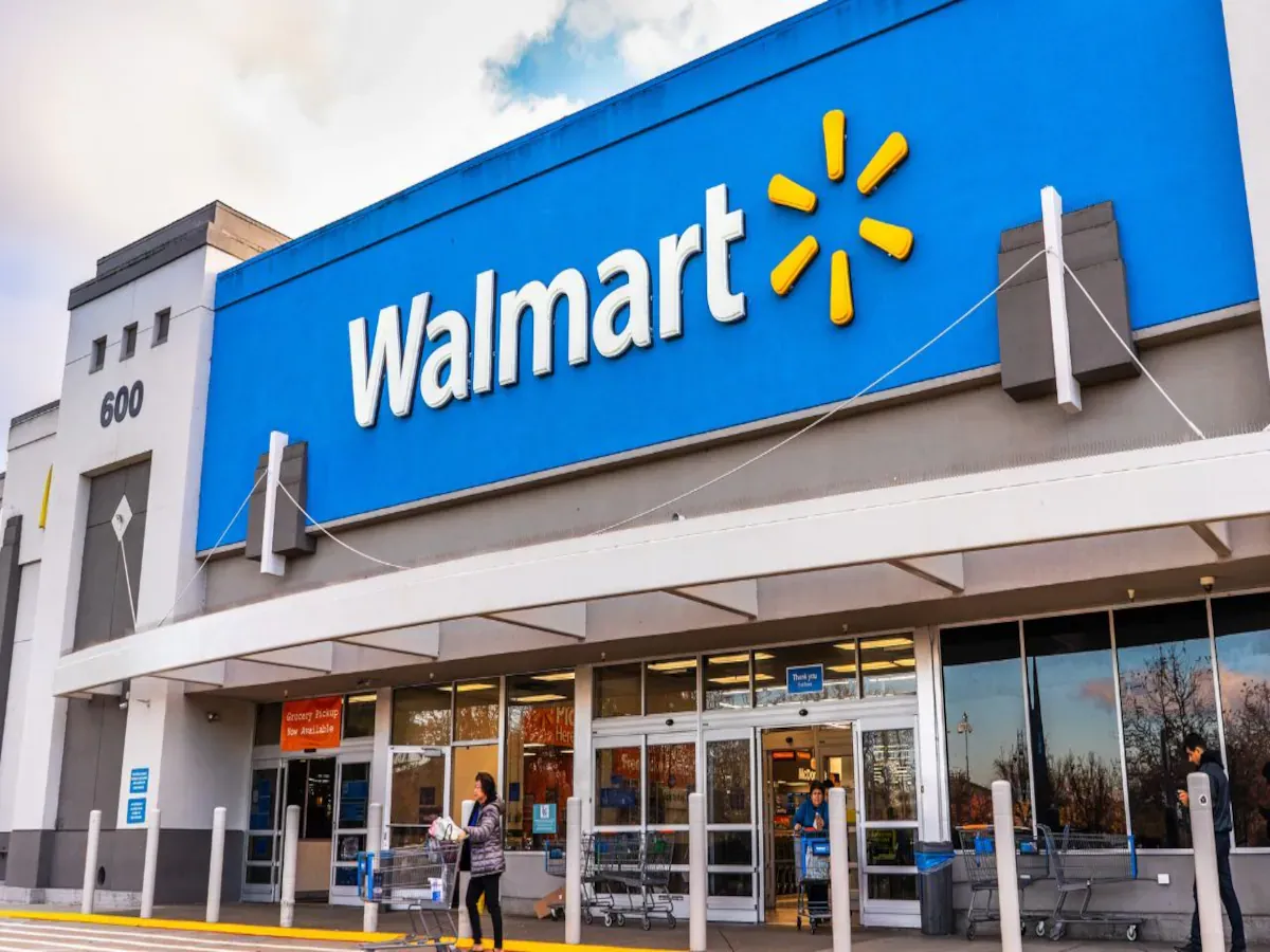 Walmart employee folding clothes in a store aisle, showcasing retail resilience amid tariff challenges