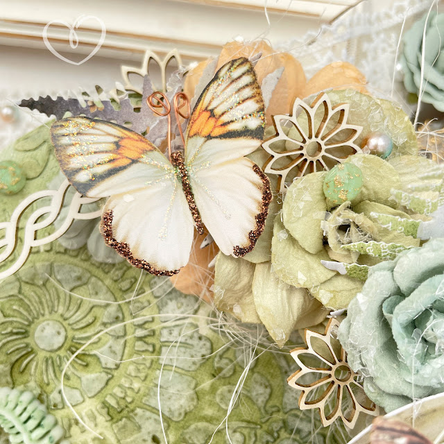 Mixed media canvas created with Tim Holtz Distress sprays; Prima Marketing In the Moment Collection flowers and ephemera; and Reneabouquets butterflies, chipboard, lace, glitter glass and pearls.