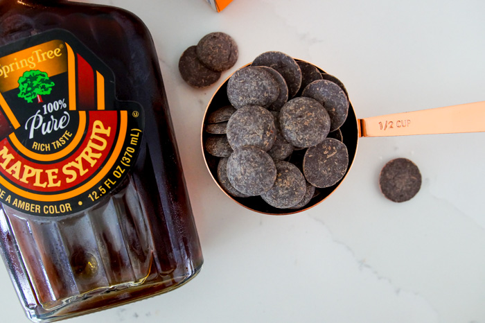 chocolate baking discs next to bottle of maple syrup