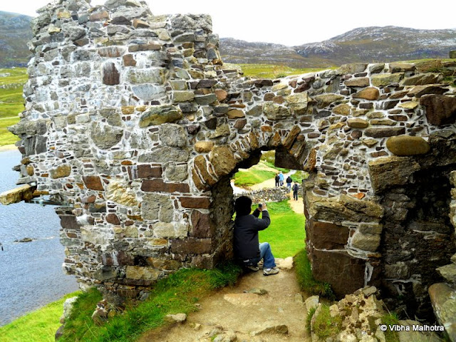 On the banks of Loch Assynt, a lake in the North-East Highlands of Scotland, are two ruins. Both of them are in advanced stages of decay and have very interesting stories linked with them.First of them is the Calda House, which was constructed in the 18th century by the members of the Clan Mackenzie. The house once used to be a three storied abode that burnt down after a lightning strike apparently because the occupants continued to celebrate on the Sabbath day of the Lord. Looking at the state of the house today, one would guess the age of the building to be much more than only a couple of centuries.This is how the Calda House would've looked when it was still inhabited and not burnt down. Look at the detailed maps. Each floor has at least 6 rooms. Sometimes it is difficult to perceive how something as big as a house can be annihilated by a local fire. Hmm. Anyways, the house is allegedly haunted by several ghosts now. I was just imagining how the area would look after the day lights faded. There were no apparent arrangements for artificial lighting. A sight of the creepy, lonely house standing miles away from any human population is enough to scare anyone. Ghosts are just garnishing.This was where our little bus was parked as well. As you can see, there's not a soul in sight for miles. Sheep don't count. And there are no bright street lights that we expect from a road.And this was how the more famous of the two ruins, the Ardvreck Castle was supposed to look like when it was not in ruins. This building is a little older than the Calda house and is very much in ruins itself as you will see in a few moments. The castle is now a risky building with the masonary ready to jump out at you at the slightest provocation. So care is advised if you visit this monument.  And this was the path we were advised to take. The path wasn't VERY boggy but it was boggy nevertheless. A bog is a wetland that contains peat that is formed by the remains of dead plants. peat is a very important fuel in these regions. The Castle was stationed on a low rocky hill next to the lake. The slippery terrain and the rocks below make this a very difficult picture to take. I think I was a little foolish to attempt this picture. Don't follow my example please. The area doesn't need any more resident ghosts. Here is the first view of the legendary Ardvreack Castle built by the members of Clan Macleod in the 16th century. The structure is imposing even in decay. This was apparently built with the support of the devil and, in exchange, one of the daughters of the Macleods was to marry the Devil. Devastated, the maiden flung herself out of a window of the castle. Her ghost is supposed to haunt the ruins till date. In front our some canoes that provided a good perspective to the picture.This is a small inlet of the Loch Assynt jutting into the castle grounds right next to the magnificient ruins. The water was clean yet grey because of the poor lighting.A view of the seemingly placid Lake Assynt from a hill on its bank. Some of the white dots in the distance are sheep grazing.A sample of what the view from the castle's windows would've been like. I wonder how people who lived in such beautiful surroundings could be so cruel to each other. Scotland's history is so full of anger, violence, hatered, and betrayal, that it isn't surprising that so many Ghosts continue to haunt these regions.My friend Andy from Taiwan clicking a risky picture.  And in the distance, visible through the window are some of our tour companions. Me and Andy were often the last ones to get back to the bus. But we were definitely a disciplined batch because we still made it in time. The canoes are finally out on the Lake. The temperatures were quite low so I bow to the courage and passion of these sailors.And here is the castle up close. Quite imposing, isn't it?