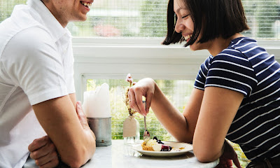 Couple smiling on a date and woman playing with food