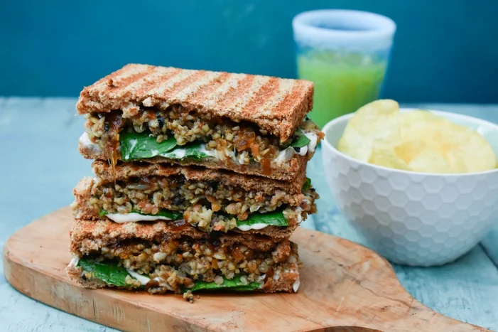 Veggie Haggis and Onion Chutney Toastie cut in half and stacked on a wooden board