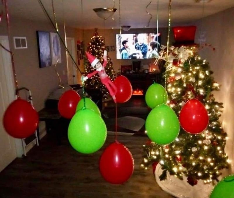 elf hanging in room full of balloons