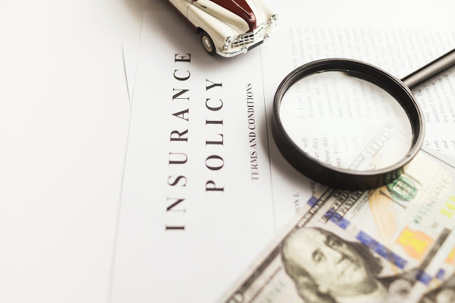 a foil with the word written "Insurance Policy" with a toy car on top and a magnifying glass on top
