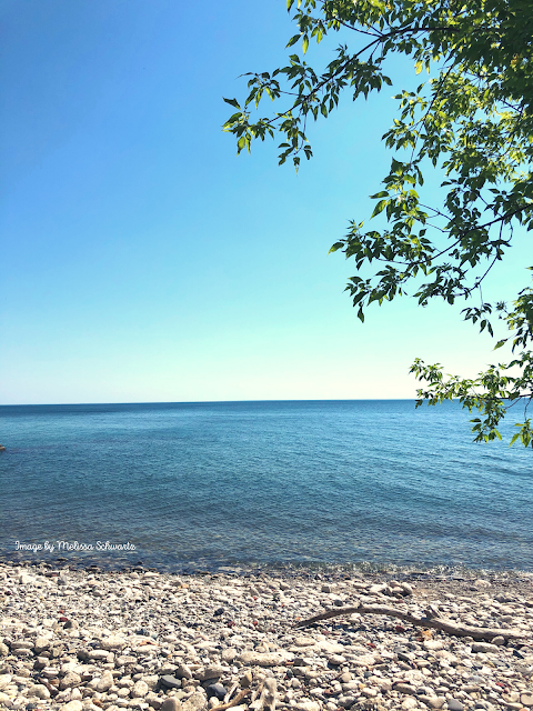 Lake Michigan gently laps upon a rocky beach at Sheridan Park in Cudahy, Wisconsin.