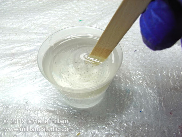 Mixing the epoxy resin with a wooden stir stick.