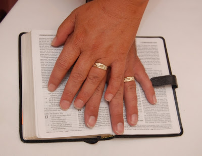hands with wedding rings on the bible opened to 1 Corinthians 13