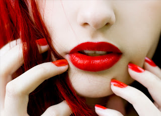 Foto de labios rojos de mujer, con uñas y cabello rojo brillante