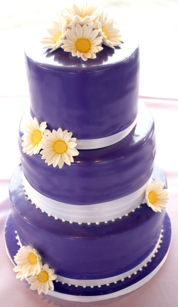 Three tier dark purple wedding cake with a glossy purple icing and white