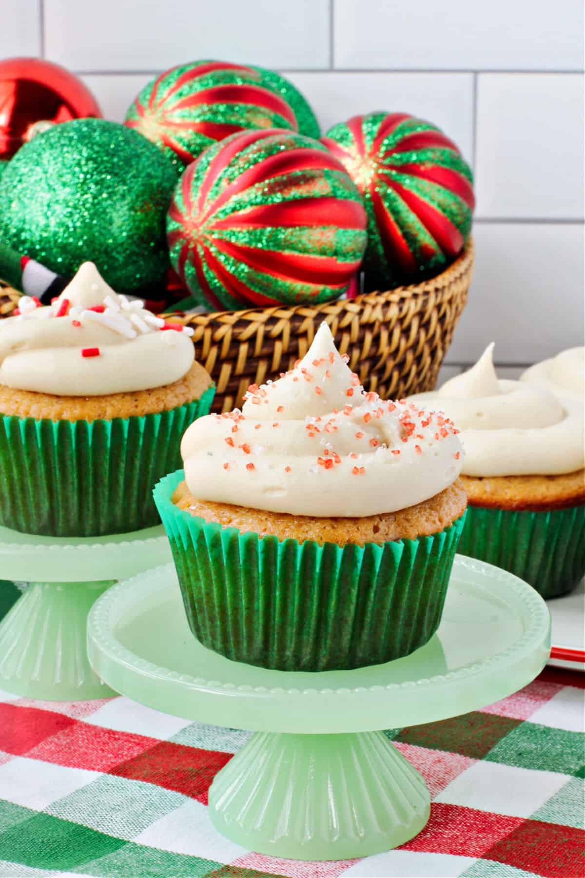 Maple cupcakes on little green cake stands with a basket in the back.