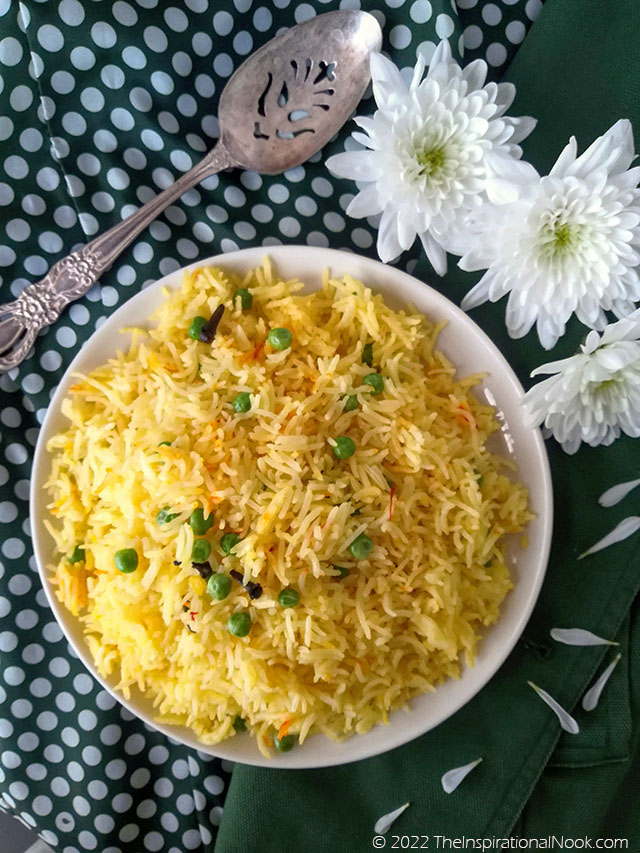 Yellow saffron and pea rice with white chrysanthemums and a silver spoon