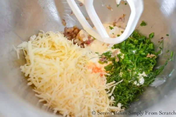 Mixing bowl with cream cheese, mayonnaise, sour cream, fontina cheese, parmesan cheese, herbs, hot sauce.