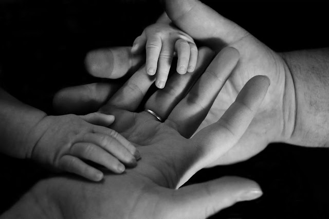 Child's hand on their father's and mother's hands