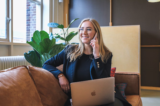 A lady working on a Macbook while talking on a phone