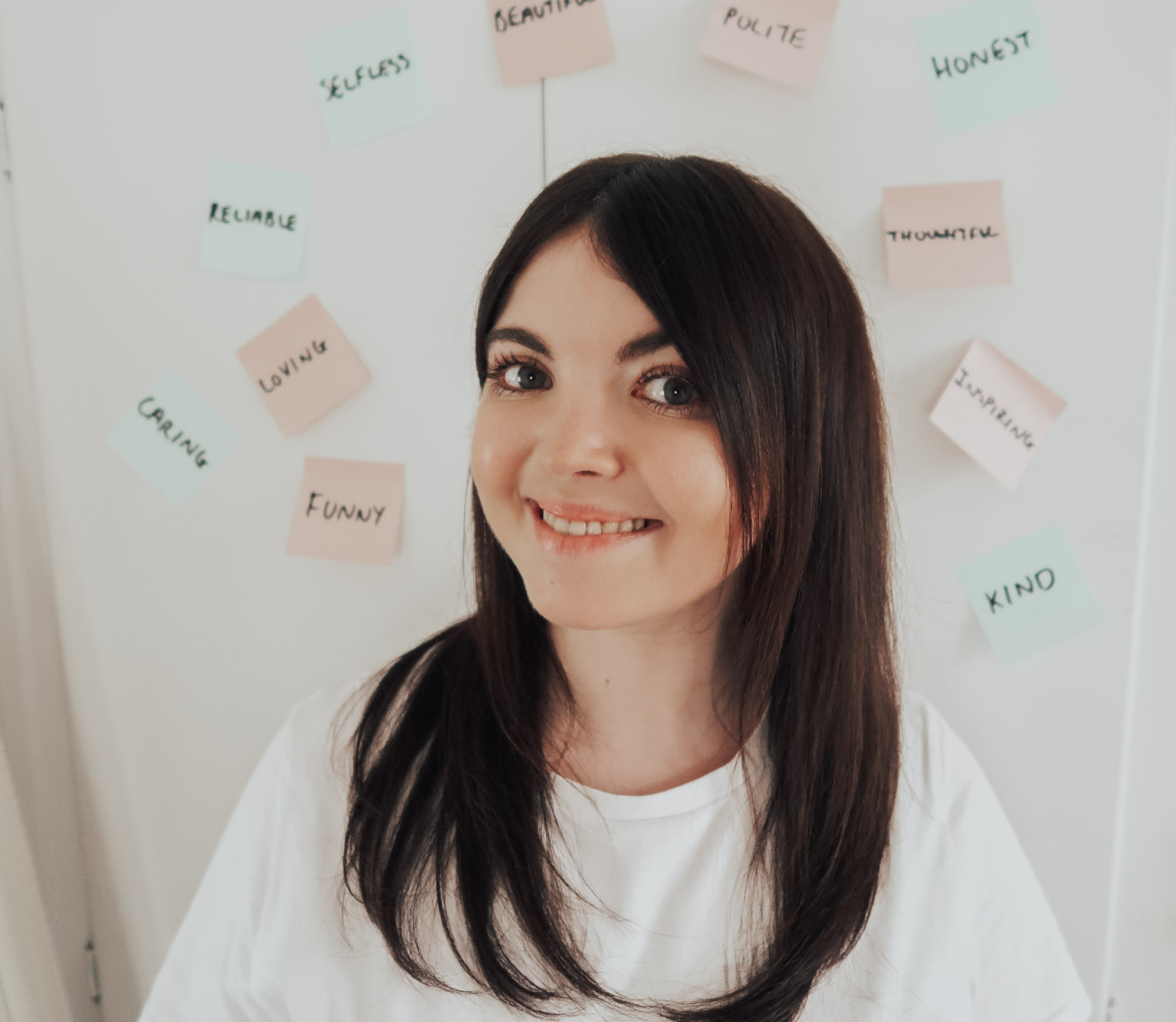 A woman smiling with sticky notes stuck on door behind her.