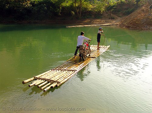 Moto atravezando rio em embarcação de bambu 