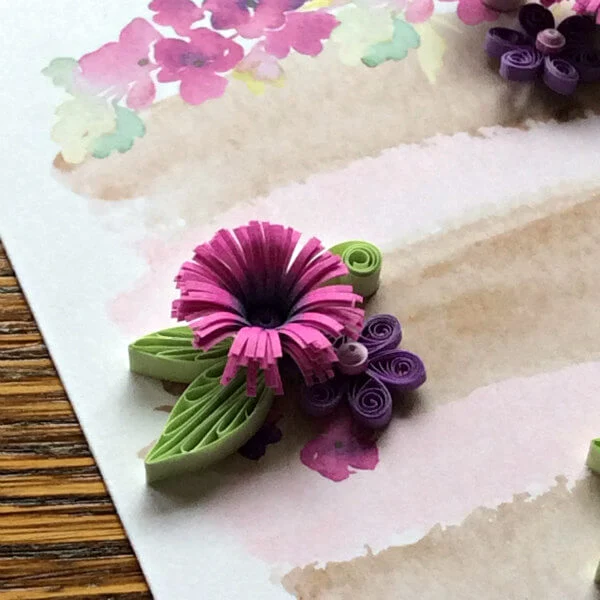 quilled flowers and leaves in pink, purple and green on a watercolor painting