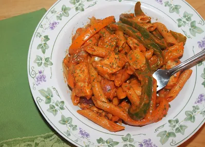 Top view of a bowl of Cajun chicken and pepper pasta.