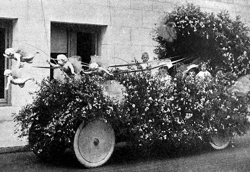 a 1917 parade float car with flowers and cherubs