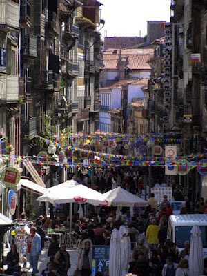 Rua das Flores enfeitada com bandeirinhas e pessoas passeando e sentadas nas mesinhas