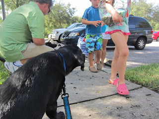 Coach is sitting on the left of the photo and staring at the little boy and girl in their swimming outfits as they walk by on the right of the photo.