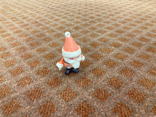 We are close enough to see Tiny Santa in this photo, as he stands on a patch of terrible carpet.