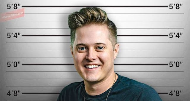 Lucas Grabeel posing in front of a height chart background