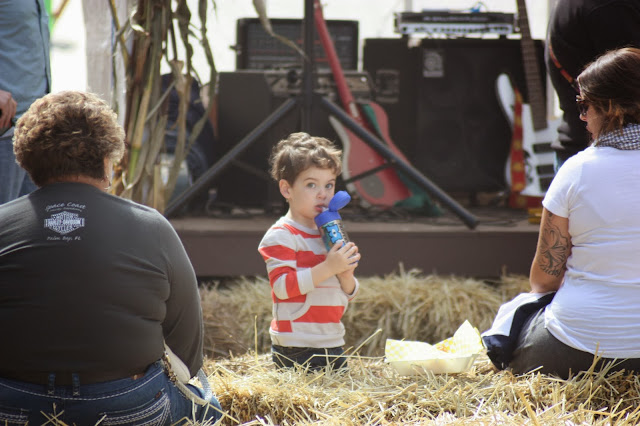 Little boy with bottle on hay bales