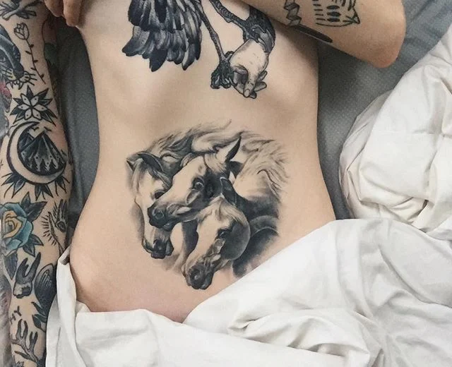 Vemos la barriga de una mujer con tatuaje de caballos