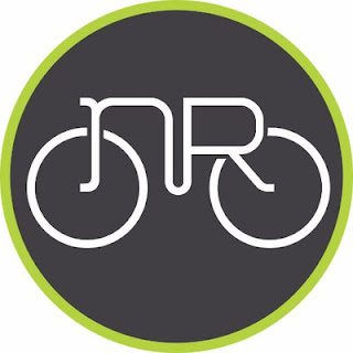 A round black logo with the outline of a bike in white in the middle, surrounded by a green ribbon