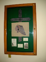 A photograph of the Lines Memorial in Baker Library, a board of materials behind glass.