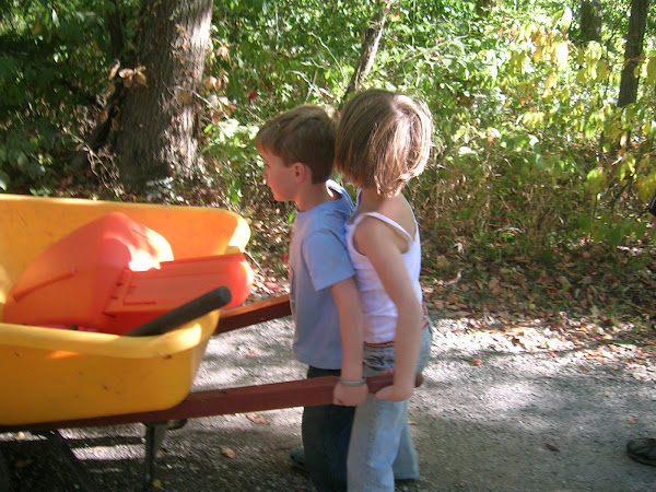 The kids attempting to push the wheelbarrow