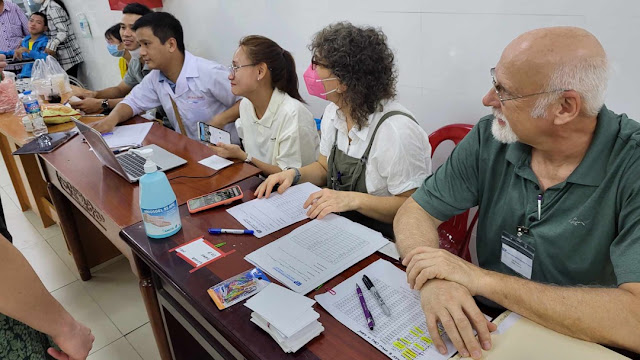 Desk with Vietnamese medical staff and IEP volunteers waiting to screen patients..