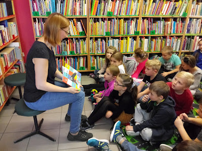 Na zdjęciu bibliotekarz czyta dzieciom książkę o "wilku, który nie lubił czytać"