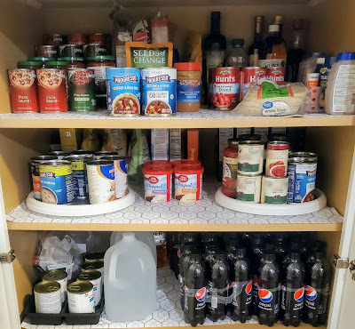 pantry shelves with canned soup, canned tomatoes, salsa, boxes of rice, boxes of noodles, and Pepsi Max bottles