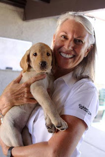 Puppy raiser Kim Hart holding a yellow Lab pup