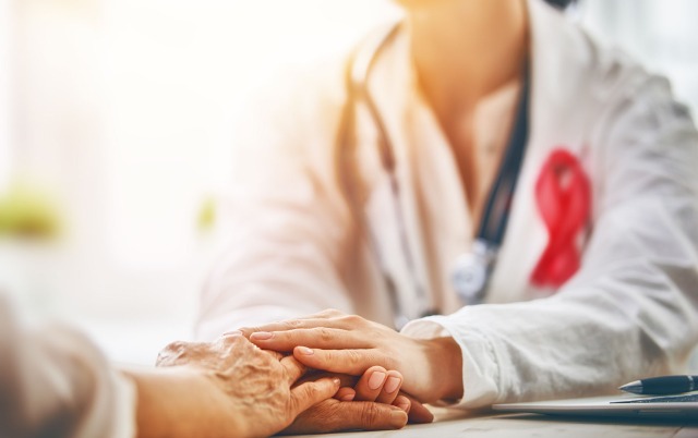 Doctor with stethoscope holding patient's hand