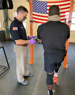 A man holding a tablet performs a single limb test on another man.