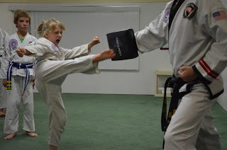 Martial arts young girl doing an awesome roundhouse kick on target