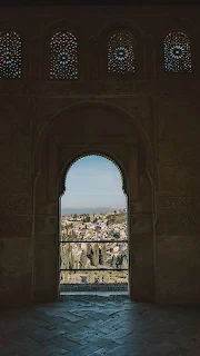 inside a cool tower of the alhambra palace, granada, looking out at the sundrenched view of the city