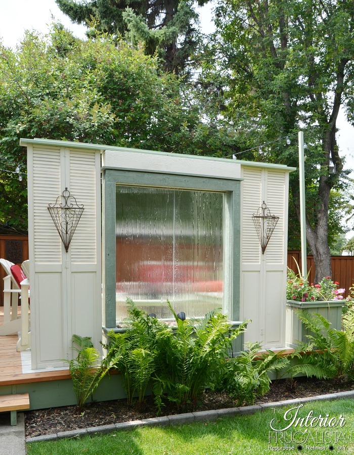 A budget-friendly Deck Privacy Screen idea made with repurposed wooden louvered bifold doors where you can see out but the neighbors can't see in!