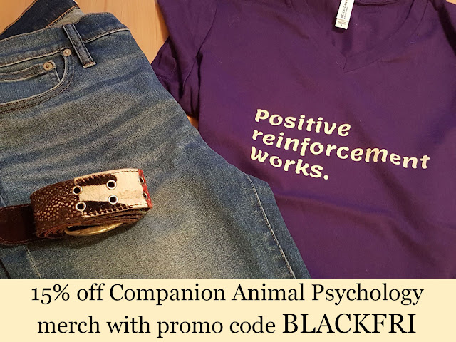 A positive reinforcement tee, jeans, and a belt, along with the promo code for 15% off Companion Animal Psychology merch, BLACKFRI