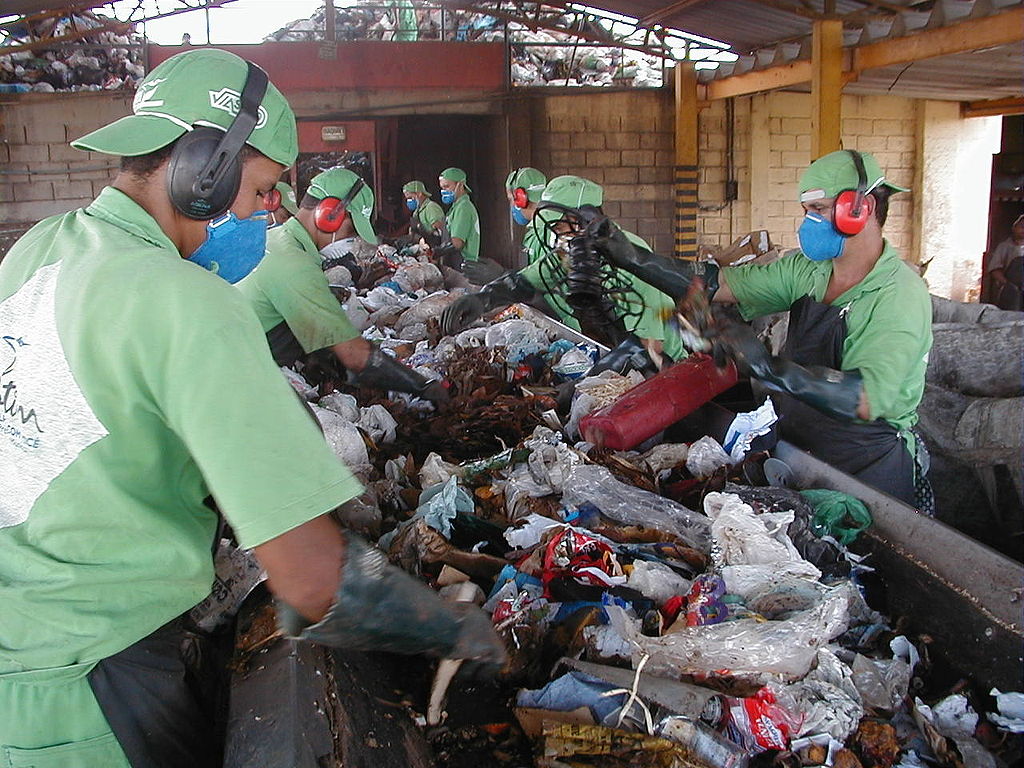 Triagem manual de lixo para reciclagem. Autor: Ignácio Costa. Fonte: https://pt.wikipedia.org/wiki/Ficheiro:TriagemDeLixo.jpg