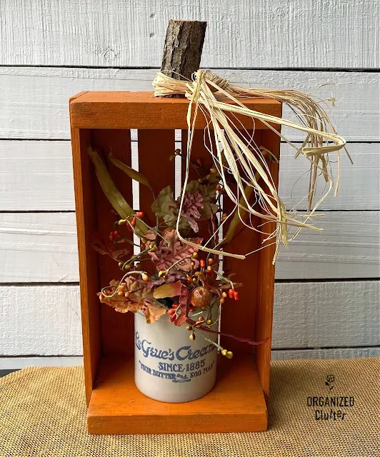 Photo of a crate pumpkin holding fall foliage