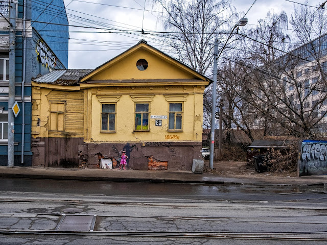 Девочка держит щенка на поводке, а на фоне уже взрослая женщина держит взрослую собаку