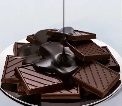 Rich hot fudge sauce in a glass jar with a spoon dipped inside