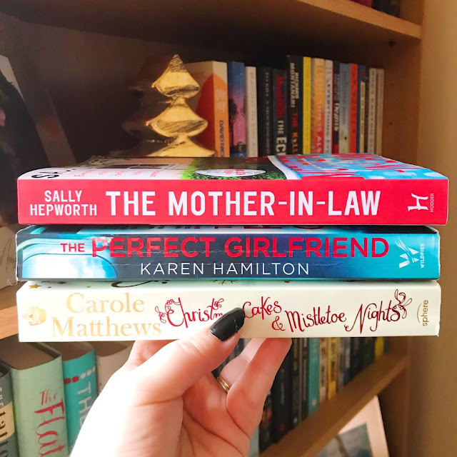 books stacked on top of each other held up in front of bookshelf